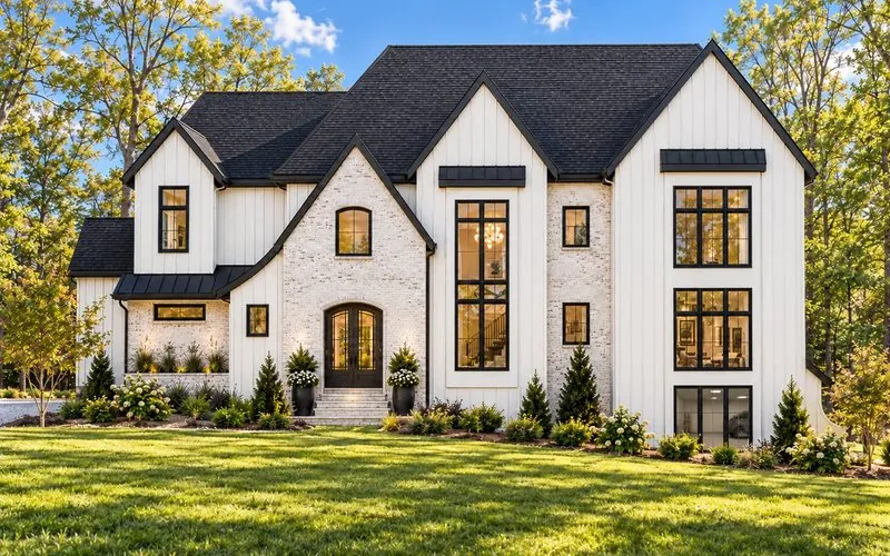 Rendering of Lot 28 on Juniper Lane, a two-story white board-and-batten home with a brick entry and tall black windows